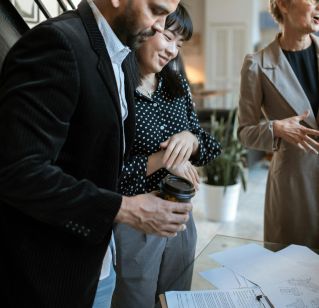 Three adults discussing business plans around a table in a modern office setting.